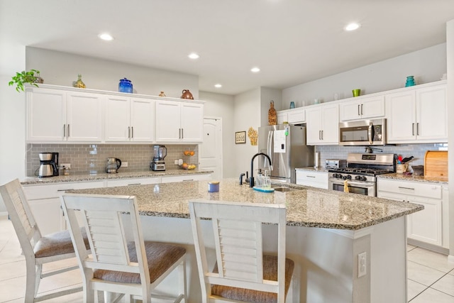 kitchen with stainless steel appliances, a sink, backsplash, and light tile patterned flooring