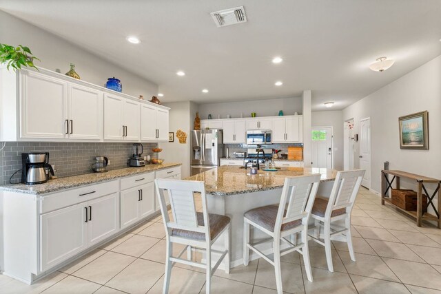 kitchen featuring tasteful backsplash, visible vents, stainless steel appliances, and light tile patterned floors