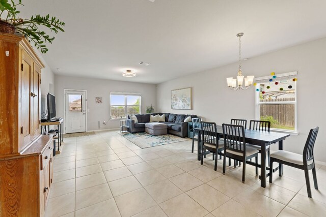 dining space with a chandelier, baseboards, and light tile patterned flooring