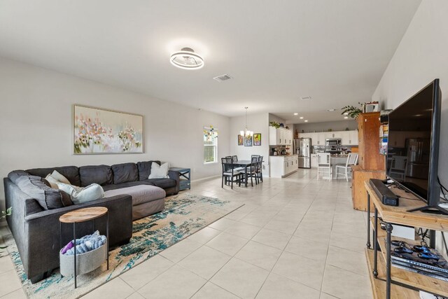 living area featuring baseboards, visible vents, a notable chandelier, and light tile patterned flooring