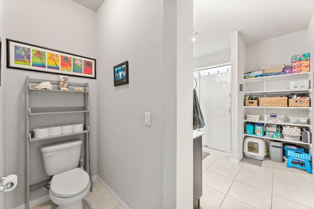 bathroom with toilet, tile patterned flooring, walk in shower, and baseboards