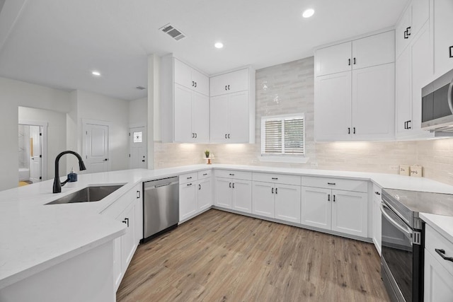 17701 Village Dr, Dripping Springs, TX 78620 - kitchen with a sink, stainless steel appliances, light wood-type flooring, backsplash, and recessed lighting
