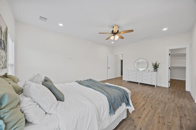 17701 Village Dr, Dripping Springs, TX 78620 - bedroom featuring wood finished floors, baseboards, a walk in closet, recessed lighting, and a ceiling fan