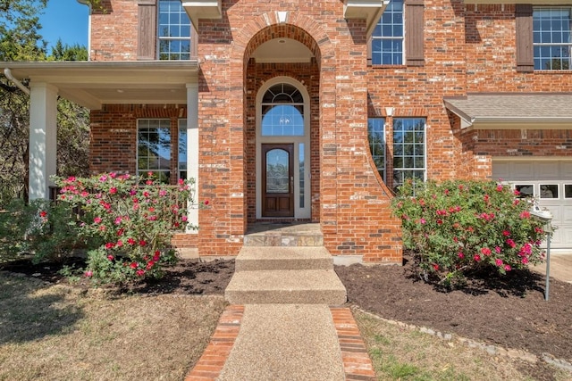 property entrance with an attached garage and brick siding