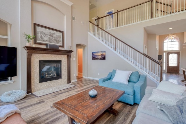 living room featuring stairway, wood finished floors, arched walkways, a towering ceiling, and visible vents