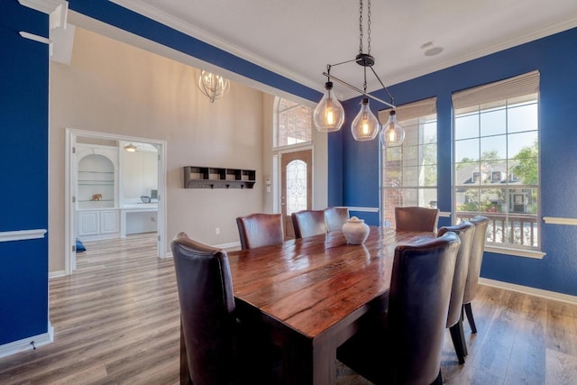 dining area with baseboards, wood finished floors, a chandelier, and ornamental molding