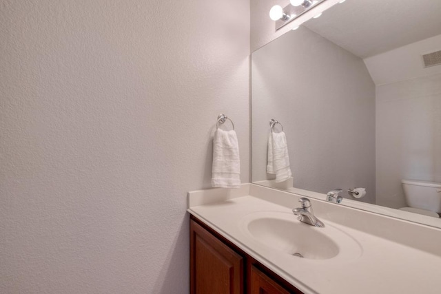 bathroom featuring visible vents, vanity, lofted ceiling, and toilet