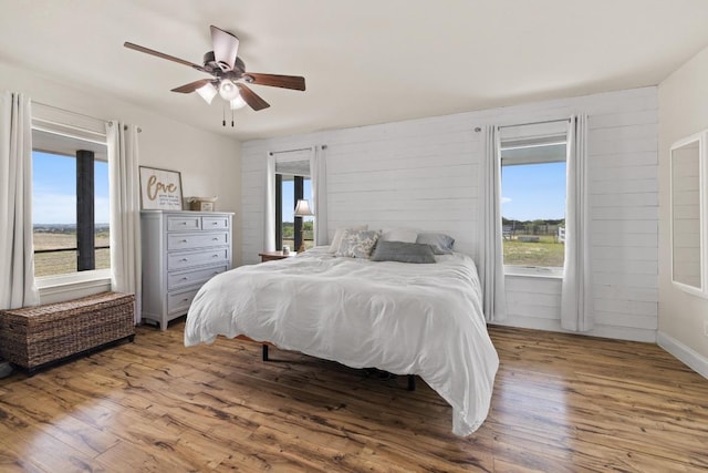 bedroom with wood finished floors, ceiling fan, and multiple windows