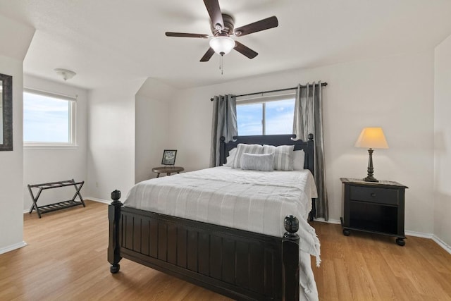 bedroom with ceiling fan, light wood-type flooring, baseboards, and multiple windows
