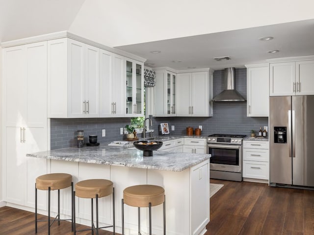 2608 S 2nd St, Austin, TX 78704 - kitchen featuring appliances with stainless steel finishes, wall chimney range hood, a sink, a peninsula, and glass insert cabinets