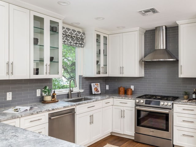 2608 S 2nd St, Austin, TX 78704 - kitchen with appliances with stainless steel finishes, wall chimney range hood, a sink, white cabinetry, and light stone counters