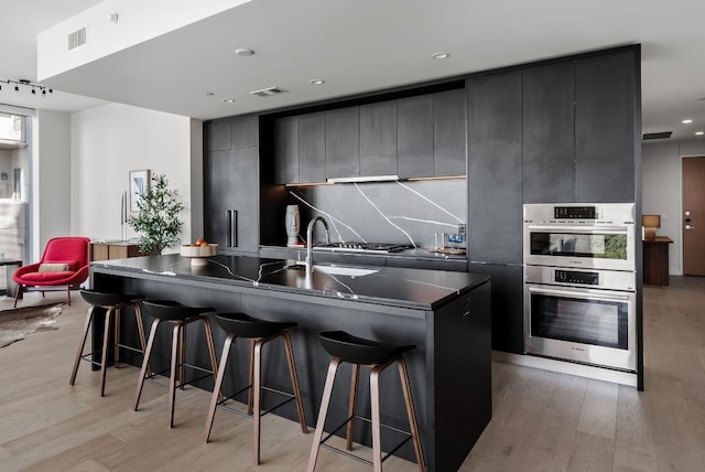 44 E Ave Unit 2301, Austin, TX 78701 - kitchen featuring light wood-style flooring, visible vents, a breakfast bar area, and modern cabinets