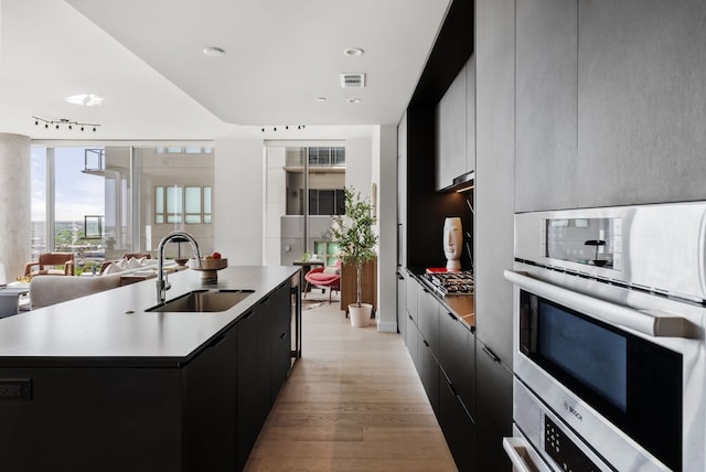 44 E Ave Unit 2301, Austin, TX 78701 - kitchen featuring dark cabinets, modern cabinets, a sink, and light wood-style floors