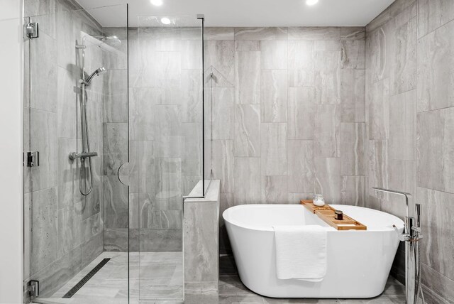 44 E Ave Unit 2301, Austin, TX 78701 - full bath featuring a shower stall, a freestanding bath, recessed lighting, and tile walls