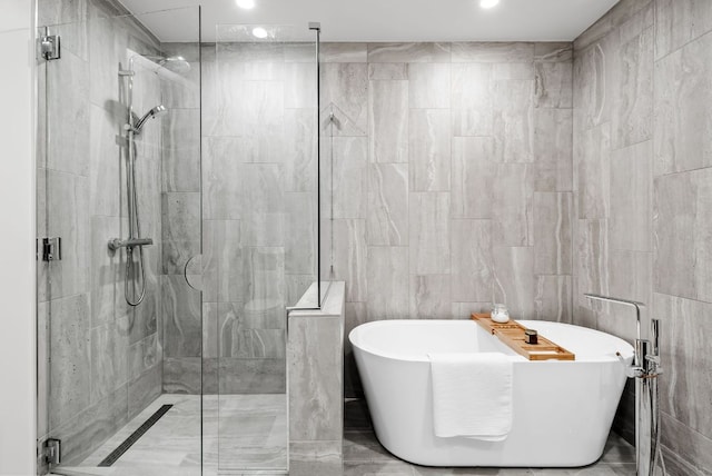 44 E Ave Unit 2301, Austin, TX 78701 - bathroom with a stall shower, tile walls, a freestanding tub, and recessed lighting