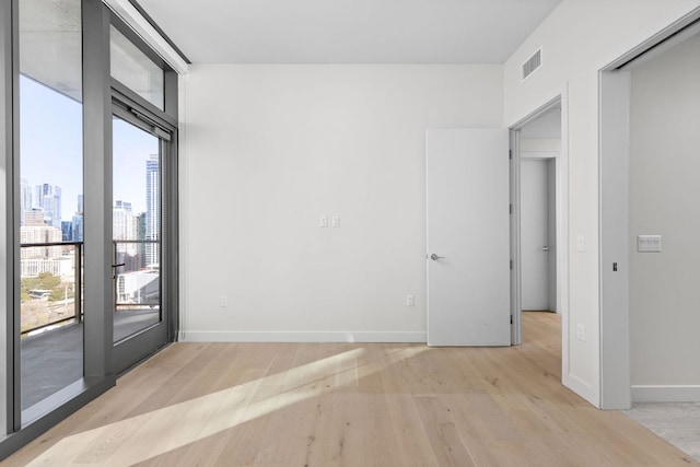 44 E Ave Unit 2301, Austin, TX 78701 - spare room with baseboards, a city view, visible vents, and light wood-style flooring