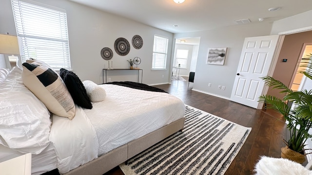 bedroom featuring wood-type flooring, visible vents, baseboards, and connected bathroom