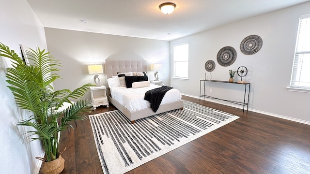 bedroom with baseboards, multiple windows, and wood finished floors