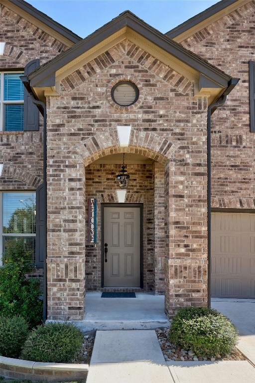doorway to property featuring brick siding and a garage