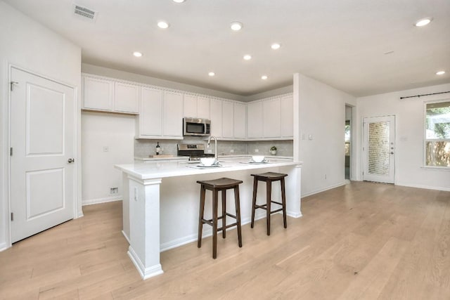141 Green Knoll Ln, Georgetown, TX 78628 - kitchen with stainless steel appliances, decorative backsplash, light wood-style flooring, light countertops, and recessed lighting