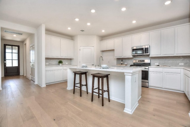 141 Green Knoll Ln, Georgetown, TX 78628 - kitchen featuring appliances with stainless steel finishes, a sink, a center island with sink, decorative backsplash, and recessed lighting