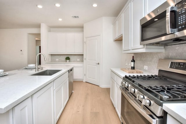 141 Green Knoll Ln, Georgetown, TX 78628 - kitchen featuring appliances with stainless steel finishes, a sink, white cabinetry, backsplash, and recessed lighting