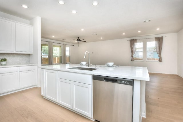 141 Green Knoll Ln, Georgetown, TX 78628 - kitchen featuring stainless steel dishwasher, a sink, light countertops, light wood-type flooring, and white cabinetry