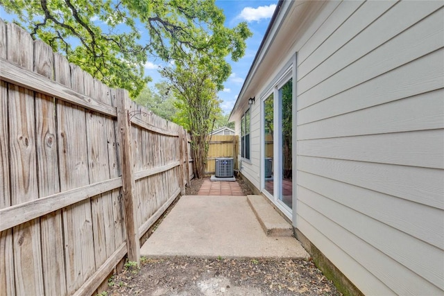 view of side of home featuring a fenced backyard, a patio, and cooling unit