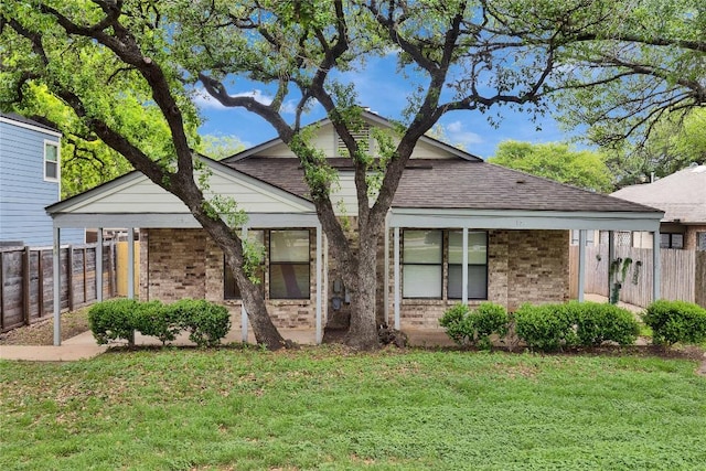 view of front of house with fence, a shingled roof, a front lawn, and brick siding