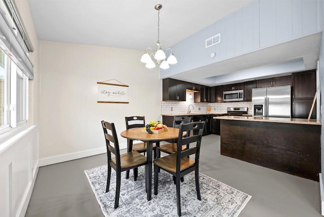 dining space featuring an inviting chandelier, concrete flooring, visible vents, and baseboards
