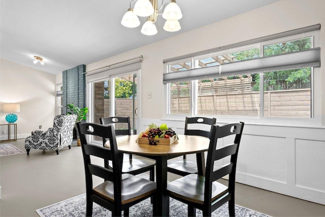 dining room with finished concrete flooring, an inviting chandelier, and lofted ceiling