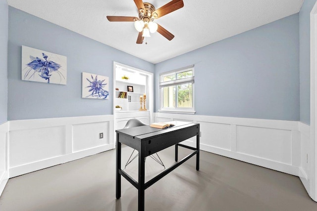office with wainscoting, ceiling fan, and a decorative wall
