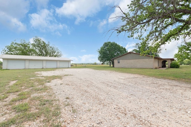 view of yard featuring driveway, an outdoor structure, and a detached garage