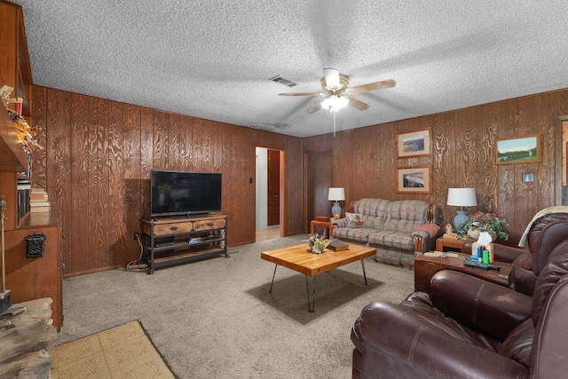 living area with carpet, wood walls, visible vents, a ceiling fan, and a textured ceiling