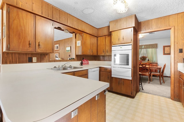 kitchen featuring a sink, brown cabinetry, white appliances, a warming drawer, and light countertops
