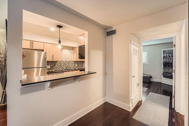 3815 Guadalupe St Unit 103, Austin, TX 78751 - kitchen with freestanding refrigerator, light brown cabinets, dark wood-style floors, backsplash, and dark countertops