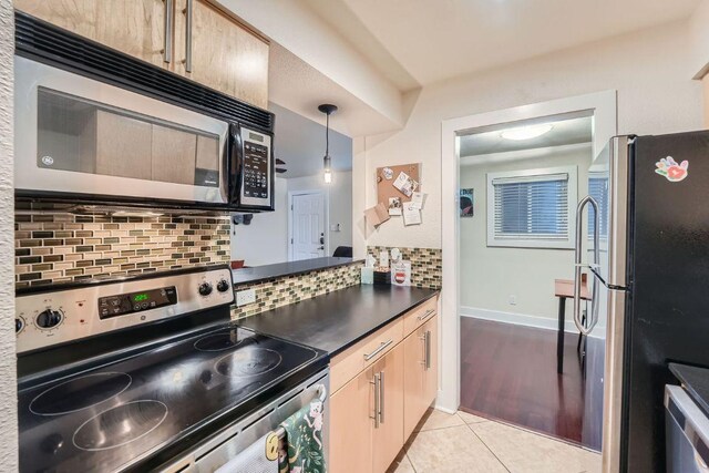 3815 Guadalupe St Unit 103, Austin, TX 78751 - kitchen with appliances with stainless steel finishes, dark countertops, decorative backsplash, light tile patterned floors, and pendant lighting