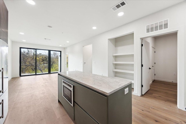 2209 S 1st St Unit 226, Austin, TX 78704 - kitchen with light wood-style floors, a kitchen island, recessed lighting, built in shelves, and open floor plan