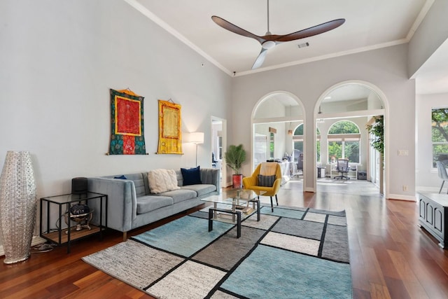living area featuring visible vents, a ceiling fan, wood finished floors, a high ceiling, and ornamental molding