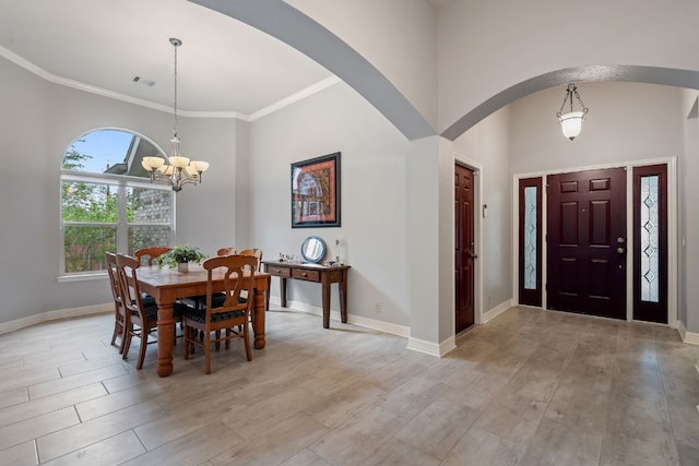 dining area with a towering ceiling, an inviting chandelier, visible vents, arched walkways, and light wood-type flooring
