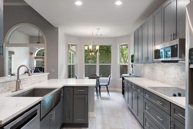 kitchen featuring a sink, an inviting chandelier, stainless steel appliances, backsplash, and recessed lighting