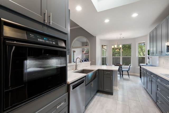 kitchen with stainless steel dishwasher, a sink, an inviting chandelier, gray cabinetry, and recessed lighting