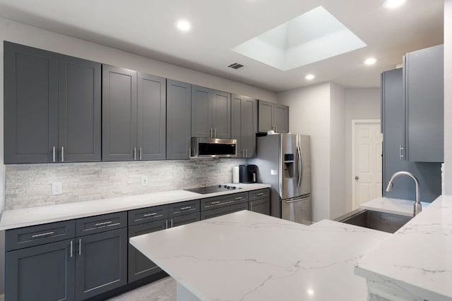 kitchen with recessed lighting, stainless steel appliances, a sink, and light stone countertops