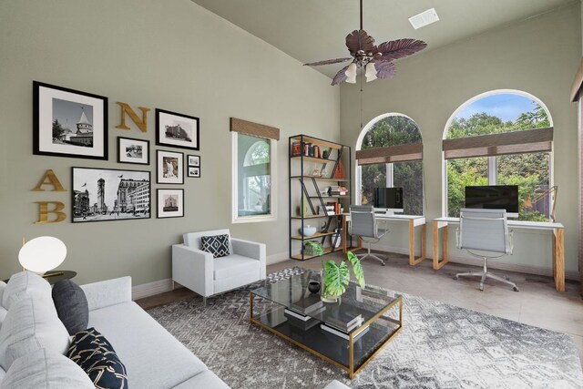 living area featuring ceiling fan, baseboards, a towering ceiling, and visible vents