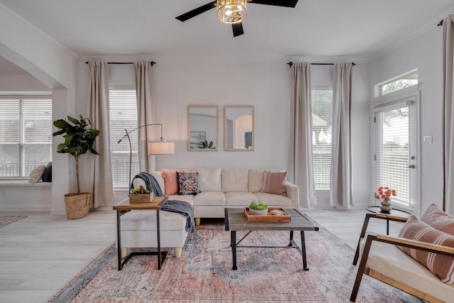 living area featuring arched walkways, wood finished floors, baseboards, and ceiling fan