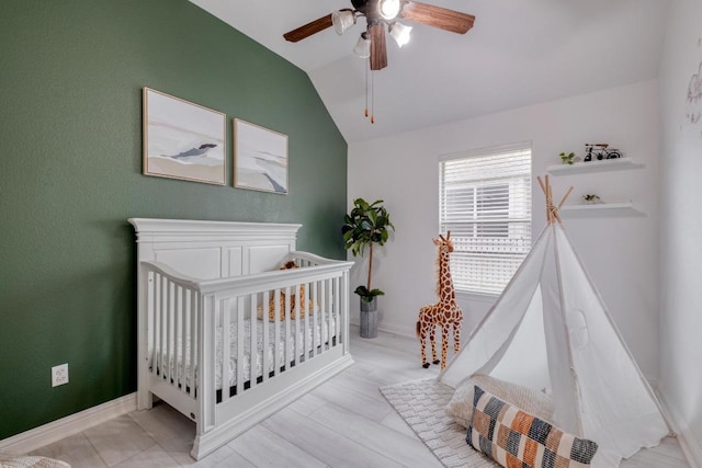bedroom with lofted ceiling, a crib, a ceiling fan, and baseboards
