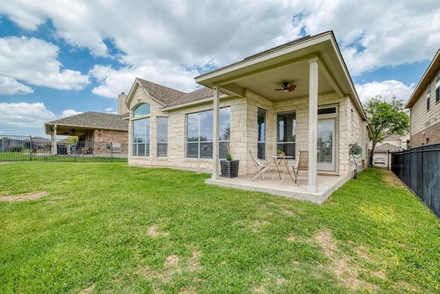 back of property with a patio area, stone siding, a fenced backyard, a yard, and ceiling fan