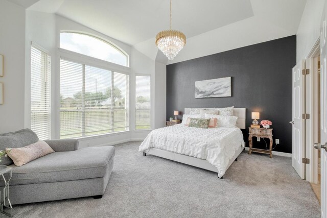 bedroom with vaulted ceiling, an accent wall, baseboards, carpet flooring, and a notable chandelier