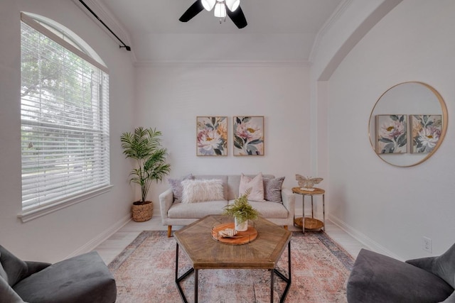 living area with ornamental molding, baseboards, and ceiling fan