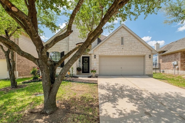 traditional home with fence, a front lawn, concrete driveway, an attached garage, and stone siding